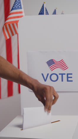 Vertical-Video-Shot-Of-Man-In-Booth-Filling-In-Ballot-Paper-In-American-Election-Casting-Vote-Into-Ballot-Box